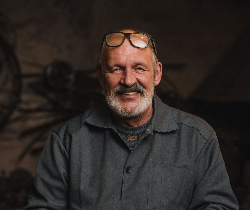 Bearded man with glasses in a workshop smiling